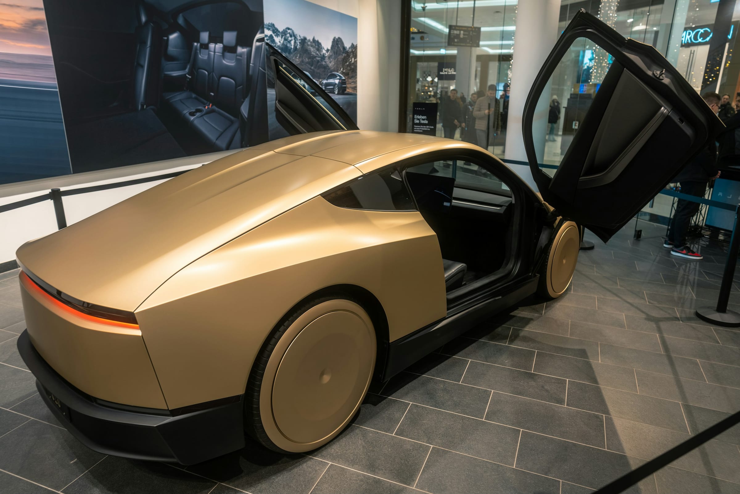 Gold Tesla Cybercab on display with doors open