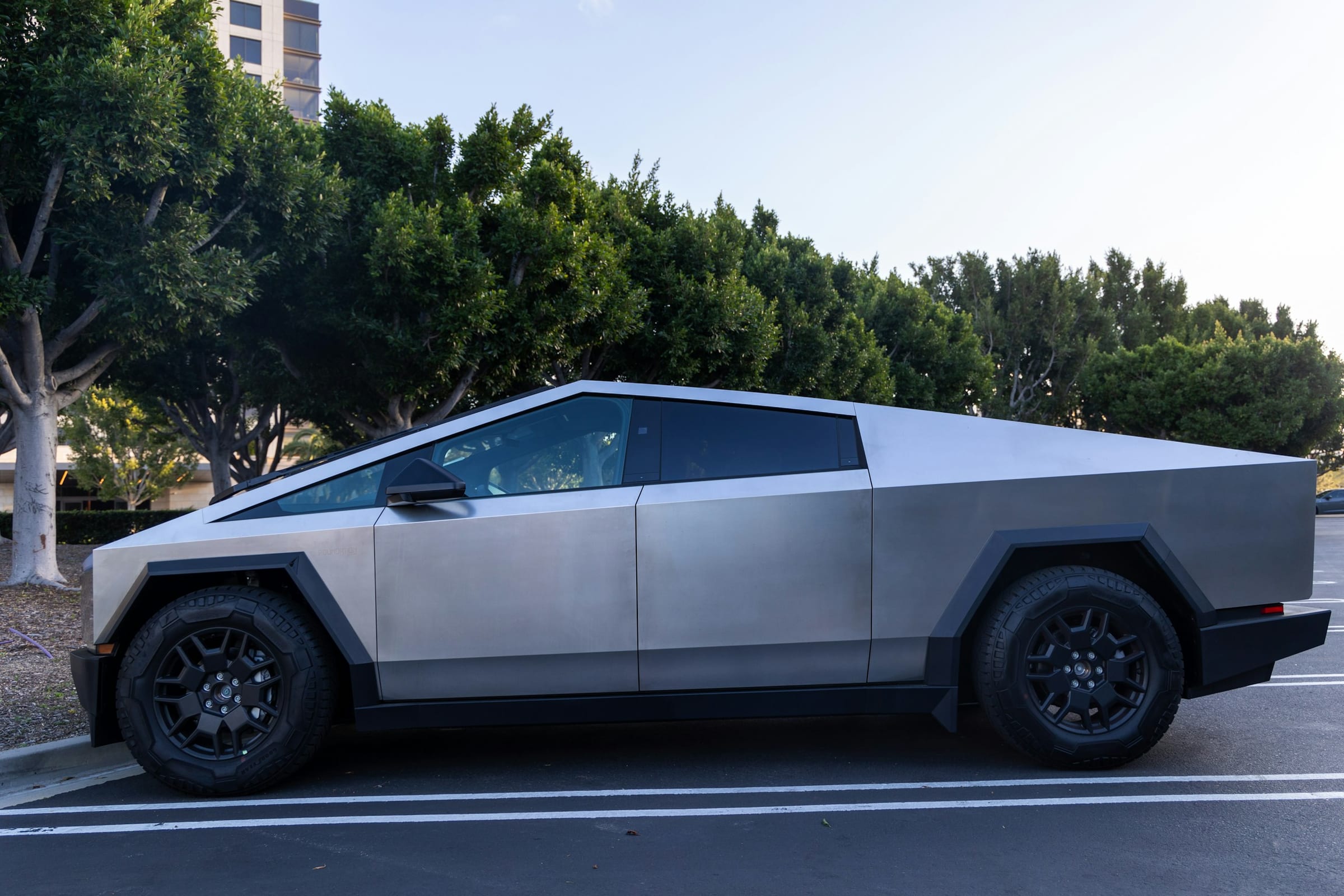 Tesla Cybertruck parked beside trees