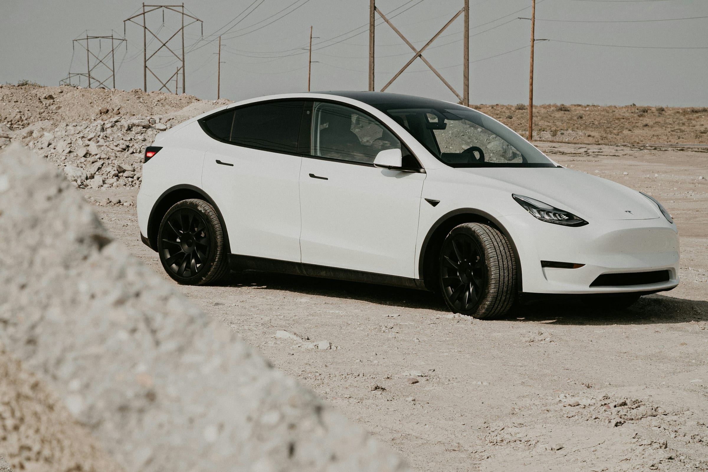 White Tesla Model Y parked on pale sand
