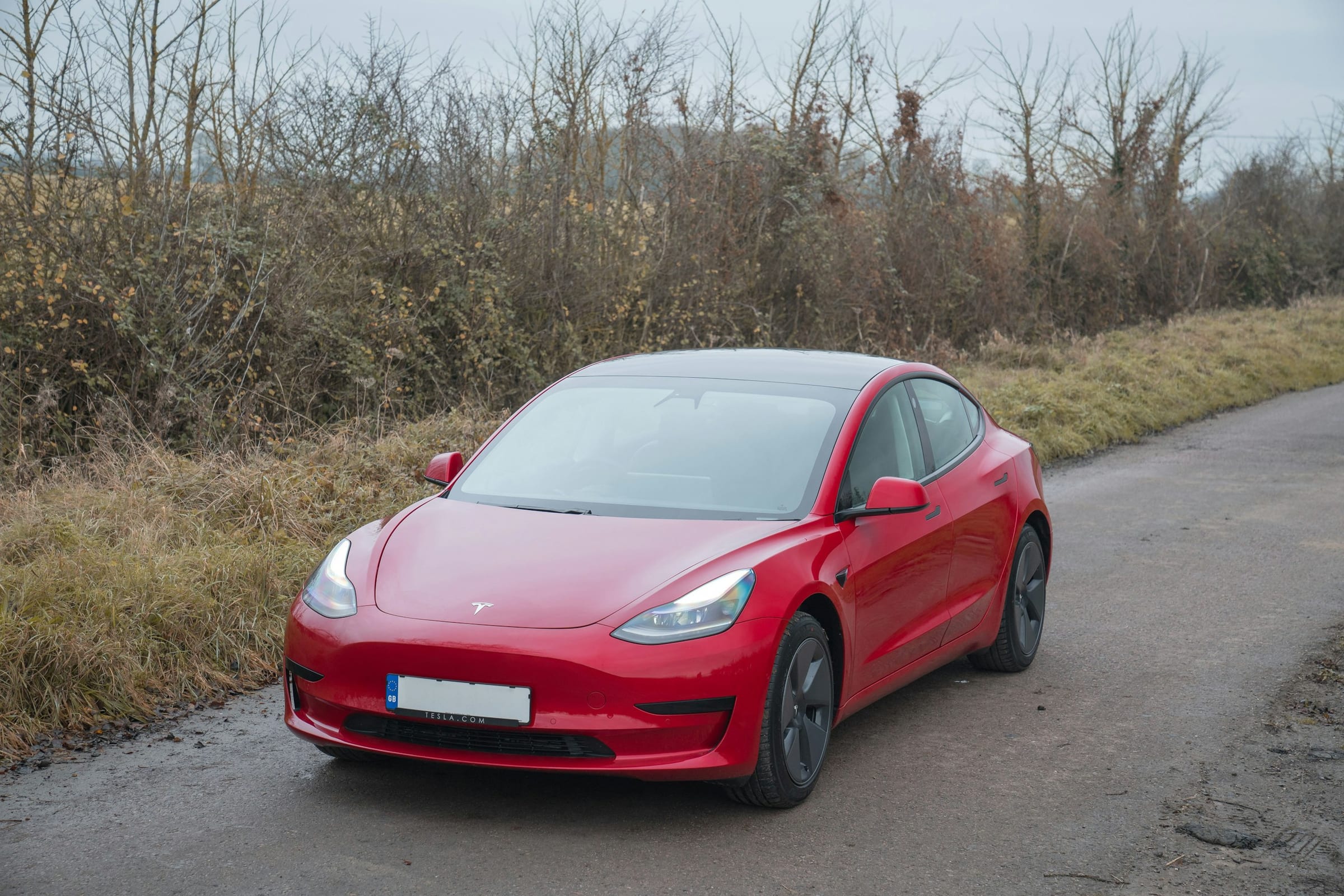 Red Tesla Model 3 on a quiet country road