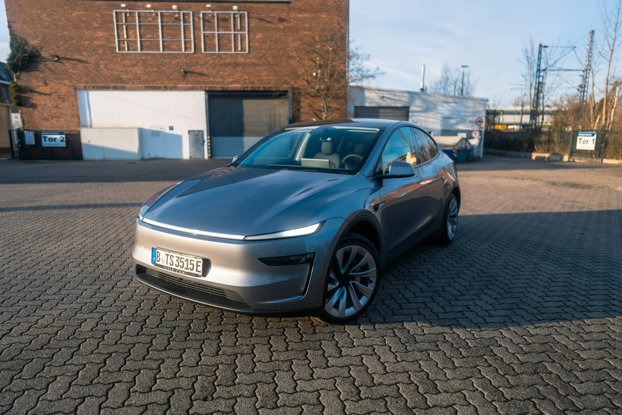 Silver Tesla Model Y parked in front of a brick building
